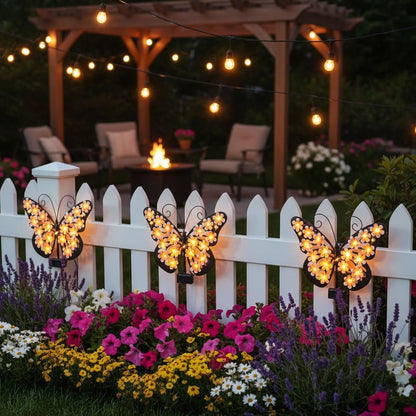 Multiple solar butterfly lights on white garden fence at night